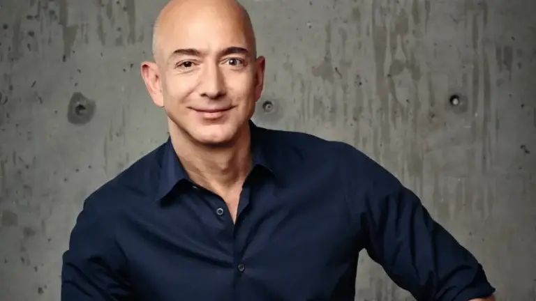 Jeff Bezos smiling in a casual blue shirt, set against a textured concrete background that echoes the straightforward and robust approach he brings to his endeavors in technology and commerce.